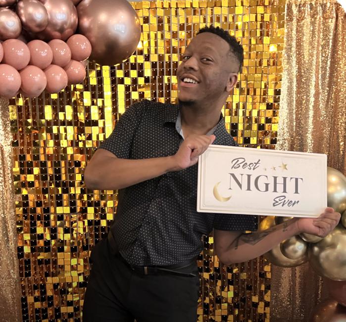 A man holding a prop that reads “Best Night Ever”